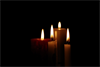 4 brennende Kerzen vor dunklem Hintergrund